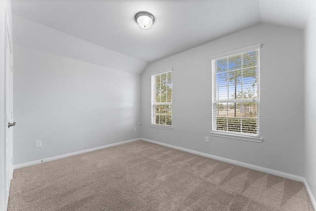 spare room with vaulted ceiling and carpet floors