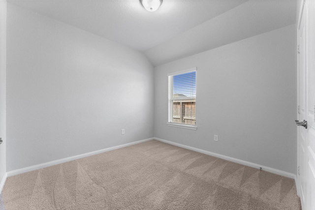 carpeted empty room featuring vaulted ceiling