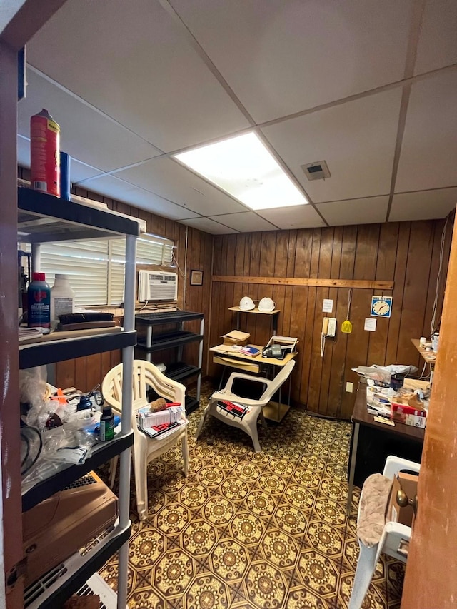 miscellaneous room featuring a drop ceiling and wooden walls