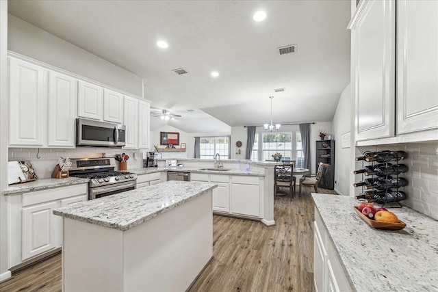 kitchen featuring appliances with stainless steel finishes, pendant lighting, sink, a center island, and kitchen peninsula