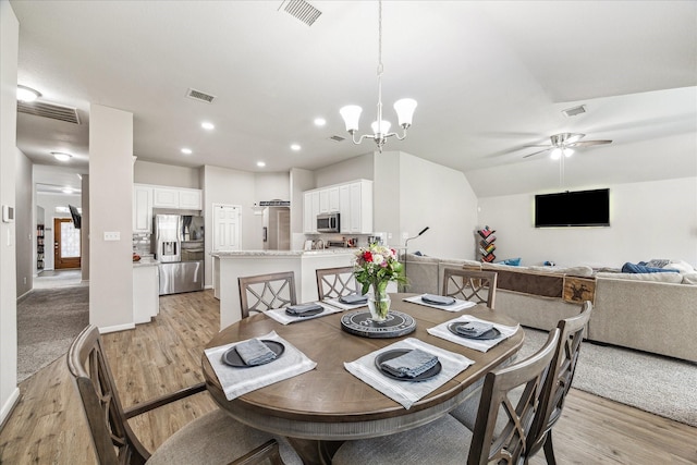 dining space featuring ceiling fan with notable chandelier and light wood-type flooring