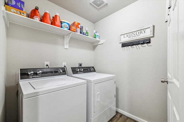 washroom with washer and dryer, a textured ceiling, and dark hardwood / wood-style floors