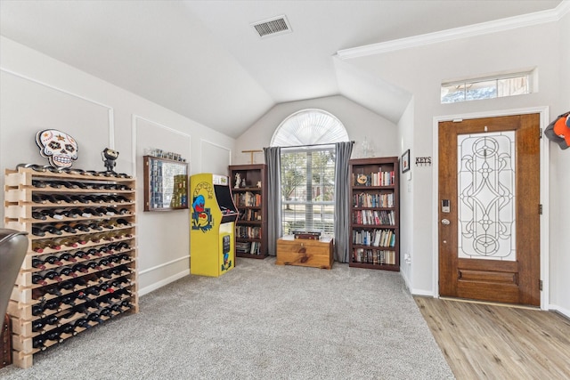 foyer featuring light hardwood / wood-style flooring, crown molding, and vaulted ceiling