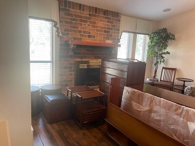 living room with dark wood-type flooring and a brick fireplace