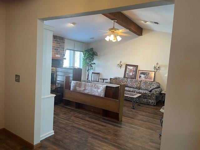 bedroom featuring vaulted ceiling with beams, dark hardwood / wood-style floors, ceiling fan, and a brick fireplace