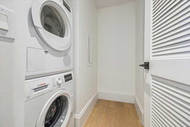 laundry area with stacked washer and clothes dryer and light wood-type flooring