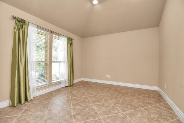 tiled spare room with vaulted ceiling