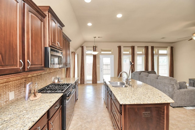 kitchen featuring sink, stainless steel appliances, light stone counters, an island with sink, and decorative backsplash