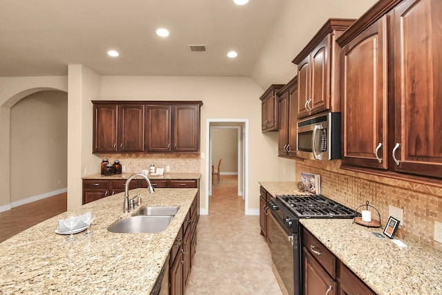 kitchen featuring range with gas stovetop, lofted ceiling, sink, decorative backsplash, and light stone countertops