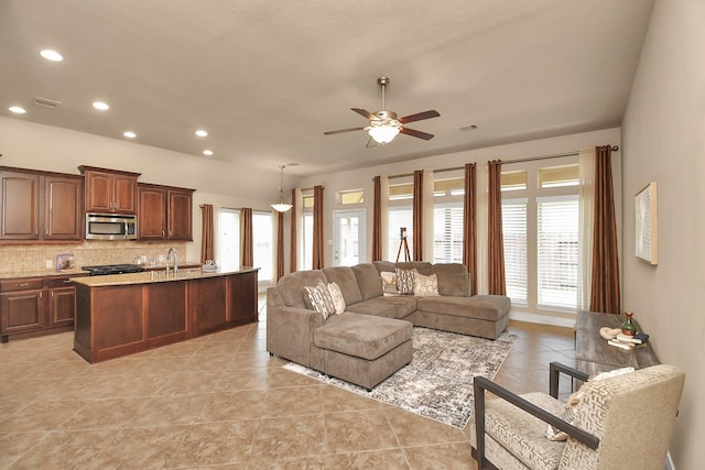 tiled living room featuring ceiling fan and sink