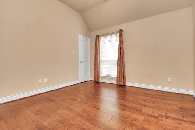 empty room with wood-type flooring and vaulted ceiling