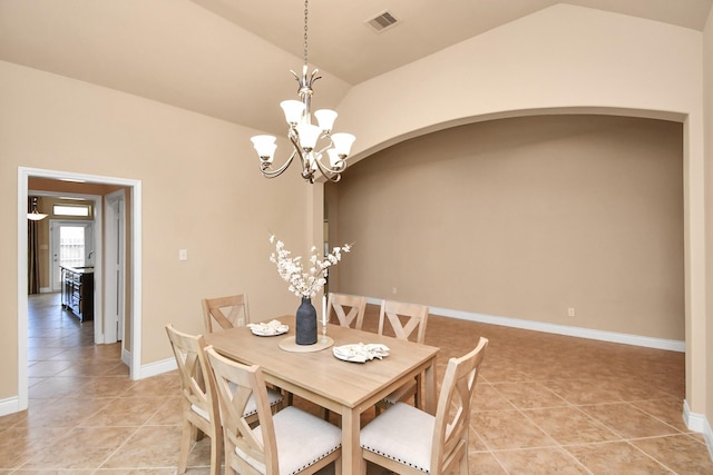 tiled dining room featuring vaulted ceiling and a chandelier