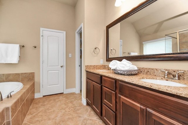 bathroom with tile patterned flooring, vanity, and tiled bath