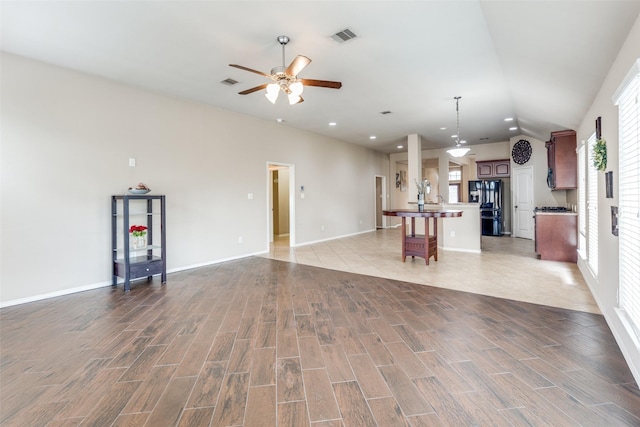 unfurnished living room with vaulted ceiling, ceiling fan, and light wood-type flooring