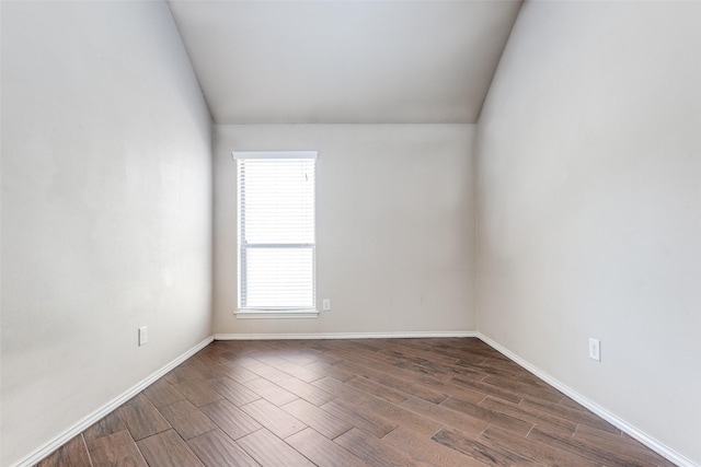 spare room featuring vaulted ceiling and dark wood-type flooring