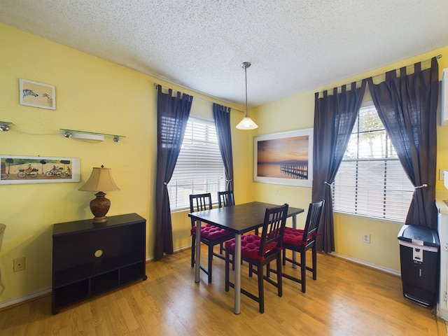 dining space with hardwood / wood-style flooring and a textured ceiling