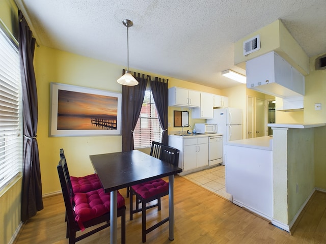 dining space with a textured ceiling and light wood-type flooring