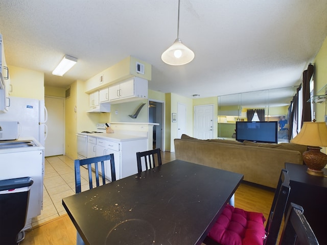 dining space with washer / dryer, light tile patterned floors, and a textured ceiling