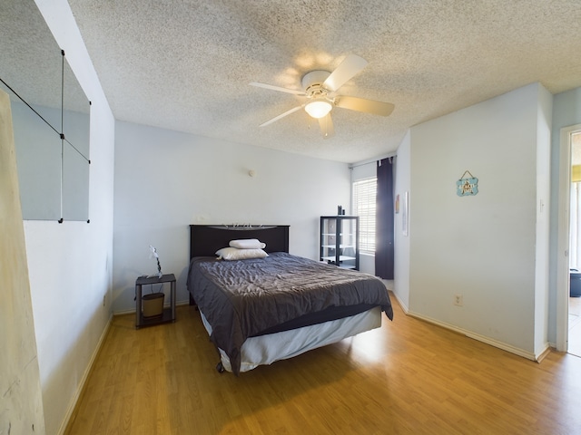 bedroom featuring ceiling fan, a textured ceiling, and light wood-type flooring