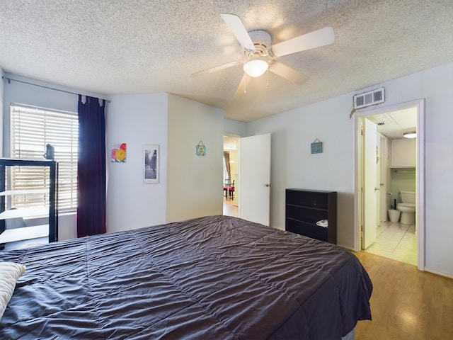 bedroom with connected bathroom, ceiling fan, light hardwood / wood-style floors, and a textured ceiling