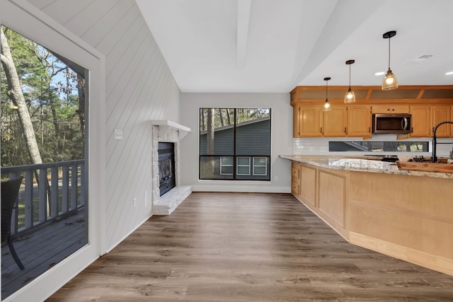 kitchen featuring vaulted ceiling, pendant lighting, dark hardwood / wood-style flooring, light stone counters, and a brick fireplace