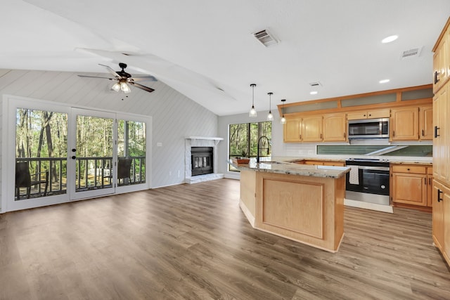 kitchen featuring sink, vaulted ceiling, appliances with stainless steel finishes, a kitchen island, and pendant lighting