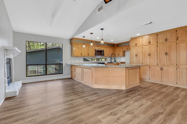 kitchen featuring pendant lighting, light stone countertops, vaulted ceiling, and light hardwood / wood-style flooring