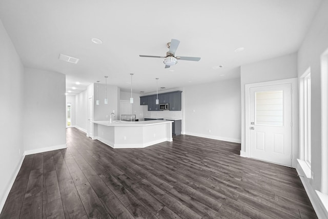 unfurnished living room with ceiling fan, dark hardwood / wood-style flooring, and sink