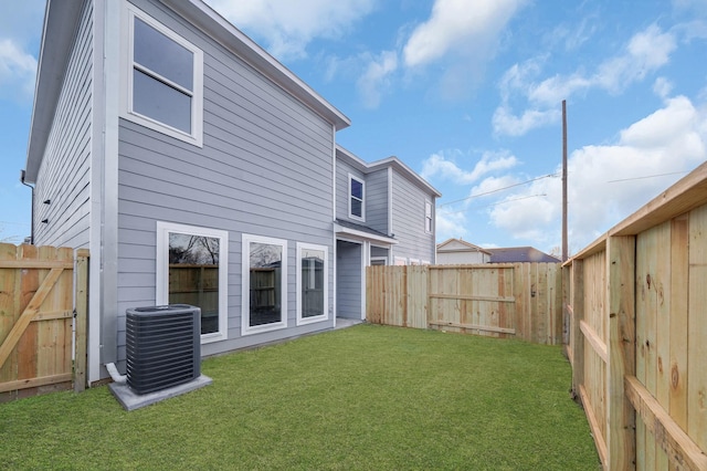 rear view of property with central AC unit and a lawn