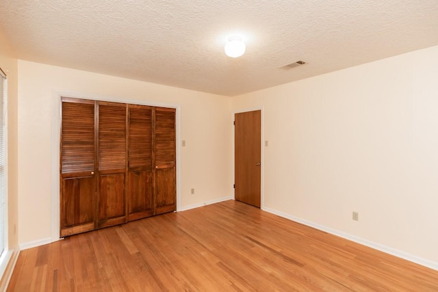 unfurnished bedroom with light hardwood / wood-style floors, a closet, and a textured ceiling