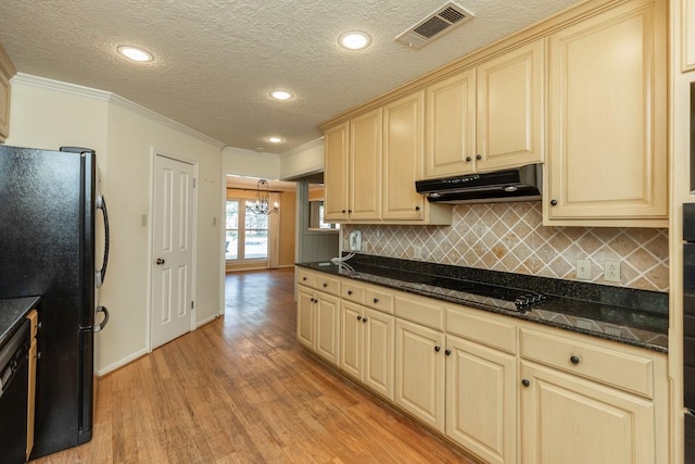 kitchen featuring crown molding, dark stone countertops, light hardwood / wood-style floors, decorative backsplash, and black appliances