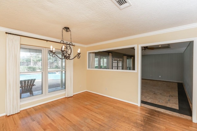 empty room with hardwood / wood-style floors, ornamental molding, and a textured ceiling