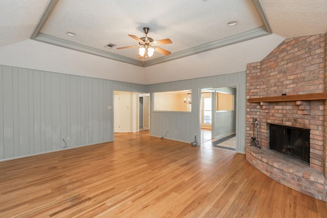 unfurnished living room featuring ceiling fan, a brick fireplace, crown molding, and light hardwood / wood-style floors