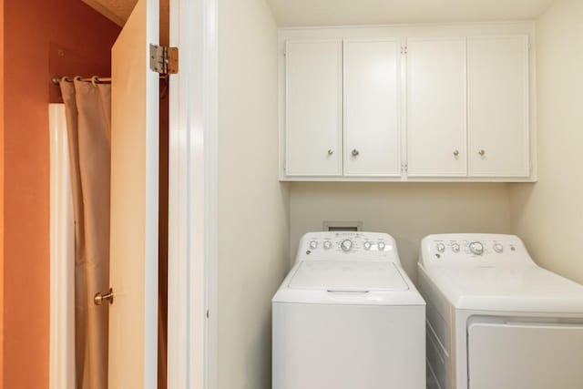 clothes washing area featuring cabinets and washing machine and dryer