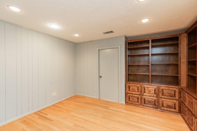 interior space with a textured ceiling and light hardwood / wood-style flooring