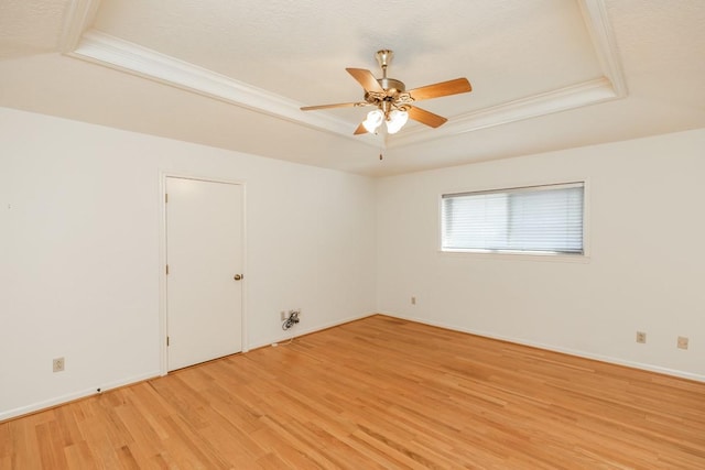 unfurnished room with ceiling fan, ornamental molding, a textured ceiling, a raised ceiling, and light wood-type flooring