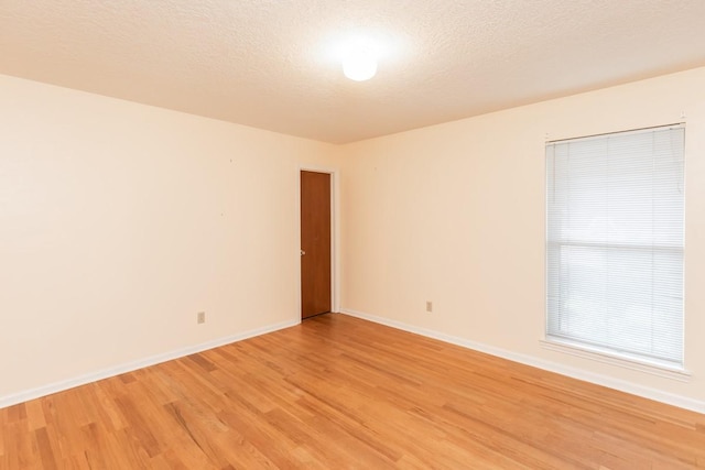 spare room featuring light hardwood / wood-style flooring and a textured ceiling