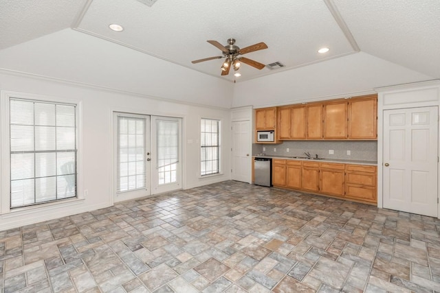 kitchen featuring vaulted ceiling, sink, stainless steel dishwasher, and french doors