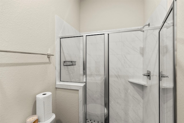 bathroom featuring a shower with door and toilet