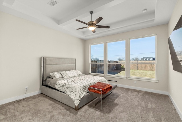 bedroom featuring light carpet, a tray ceiling, and ceiling fan