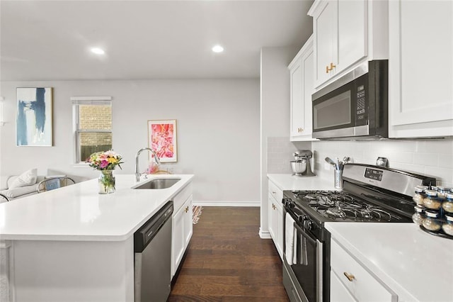 kitchen with an island with sink, appliances with stainless steel finishes, sink, and white cabinets