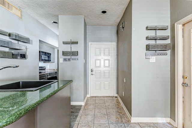 interior space featuring light tile patterned flooring, sink, and a textured ceiling