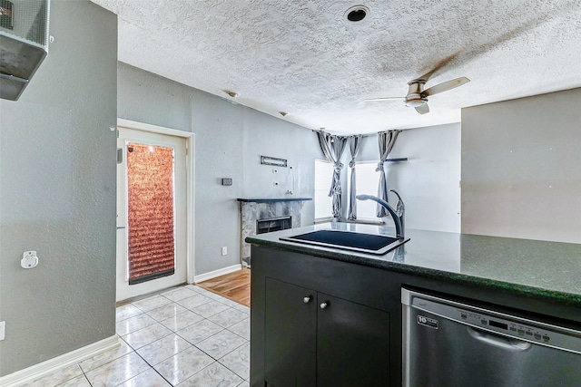 kitchen featuring sink, light tile patterned floors, ceiling fan, a textured ceiling, and stainless steel dishwasher