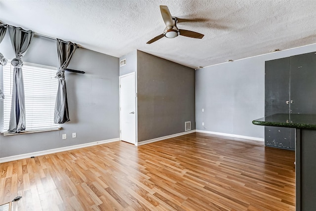 unfurnished living room with ceiling fan, hardwood / wood-style floors, and a textured ceiling