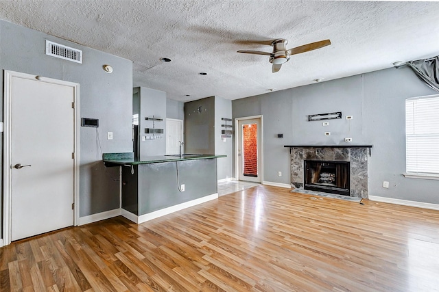 unfurnished living room with sink, a fireplace, and light hardwood / wood-style floors