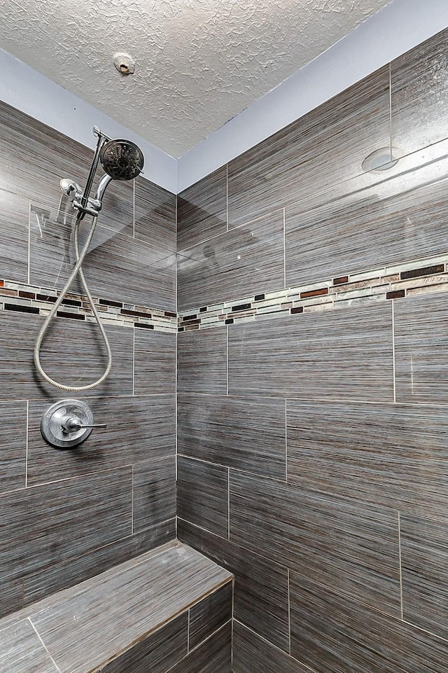 bathroom featuring tiled shower and a textured ceiling