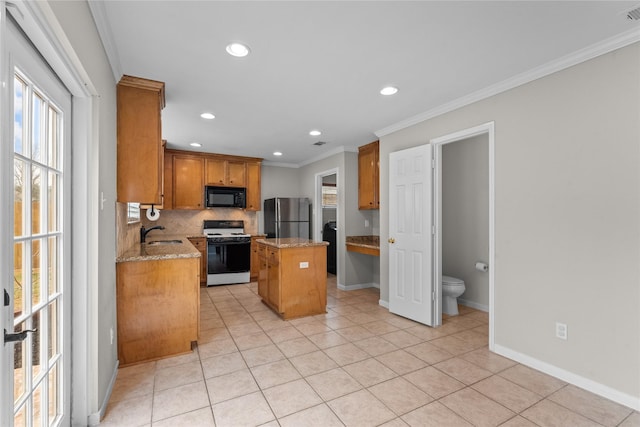 kitchen with sink, light stone counters, a center island, stainless steel fridge, and white gas range oven