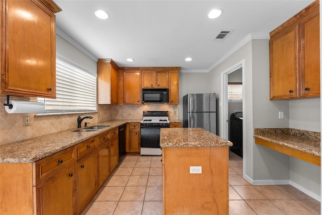 kitchen with built in desk, sink, a center island, black appliances, and light stone countertops