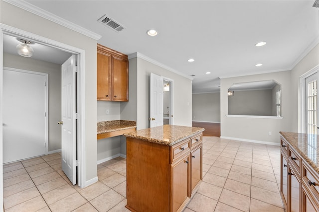 kitchen featuring light stone counters, ornamental molding, and a center island