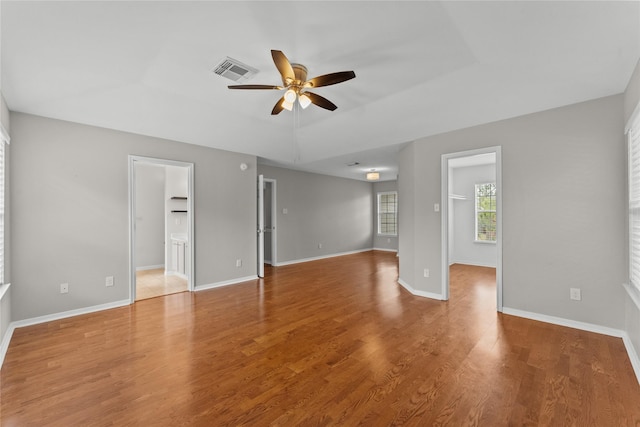 interior space with a raised ceiling, hardwood / wood-style floors, and ceiling fan